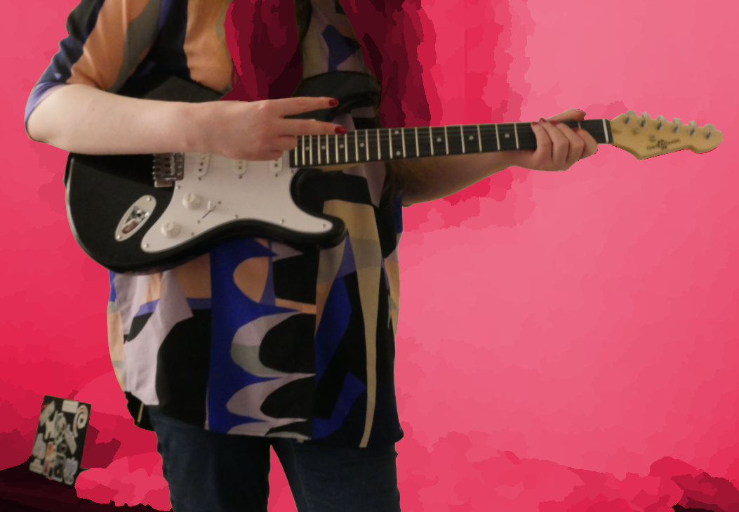 picture of me holding a black and white guitar. the background is pink and blurry.